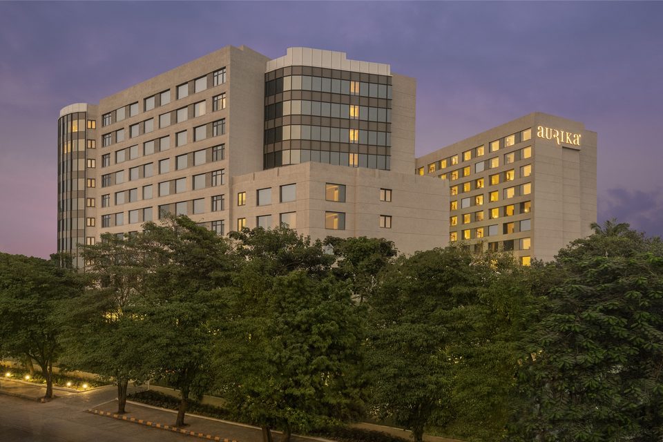 Hotel facade above green trees at dusk