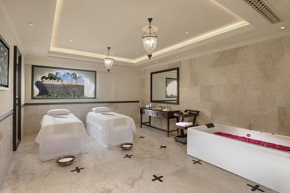 Spa treatment room with a marble bath and massage bed