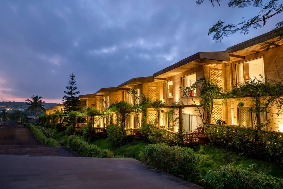 Illuminated guest accommodation beside a garden path at dusk