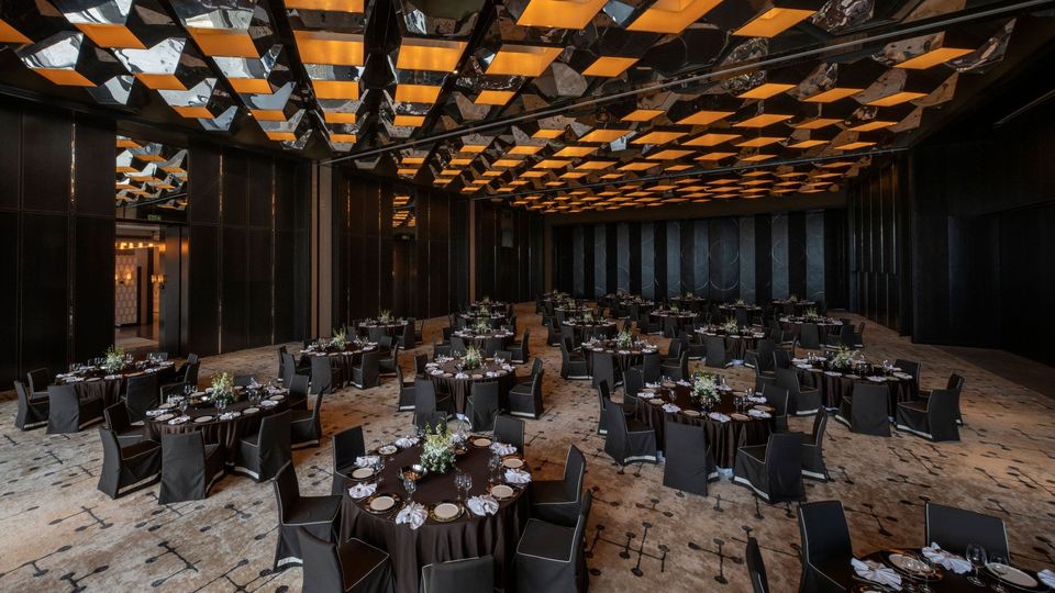 Ballroom set with round tables beneath a mirrored gold ceiling