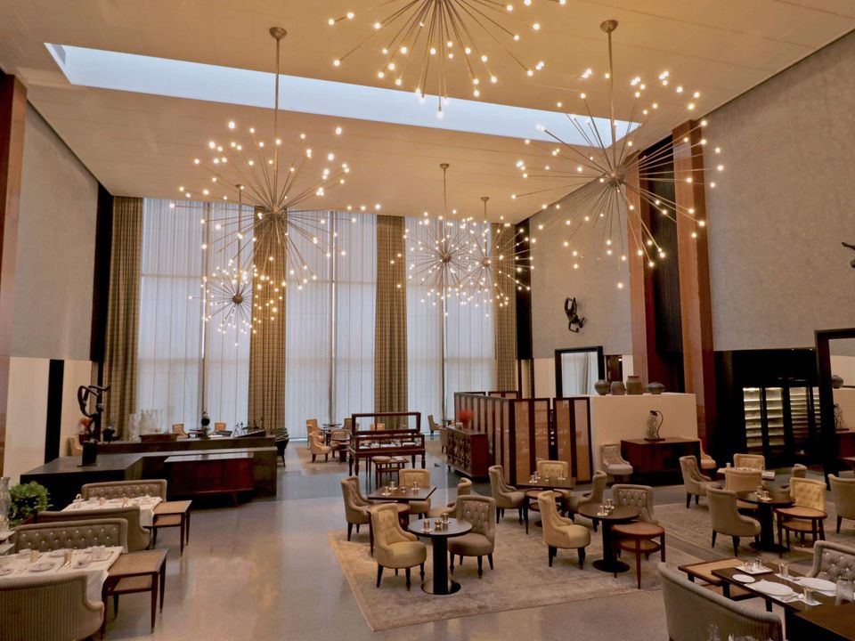 Tall lobby lounge beneath branching pendant lights