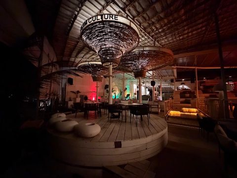 Bar and lounge seating under woven pendant lights at night at Morjim Culture