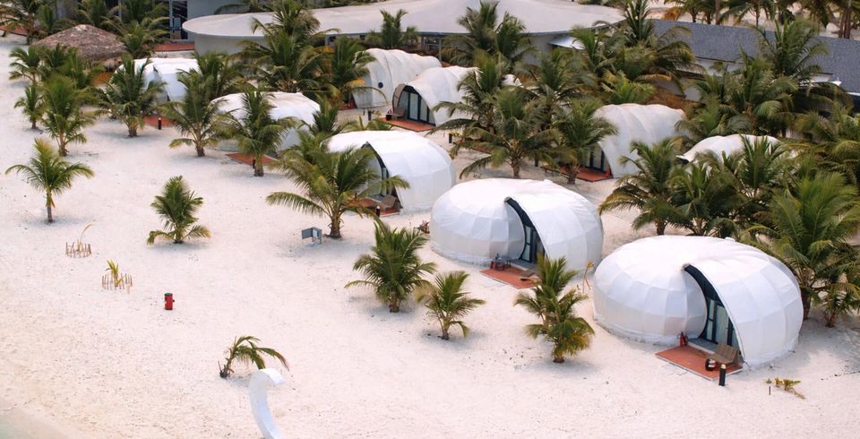 Rounded cottages among coconut palms on an island beach