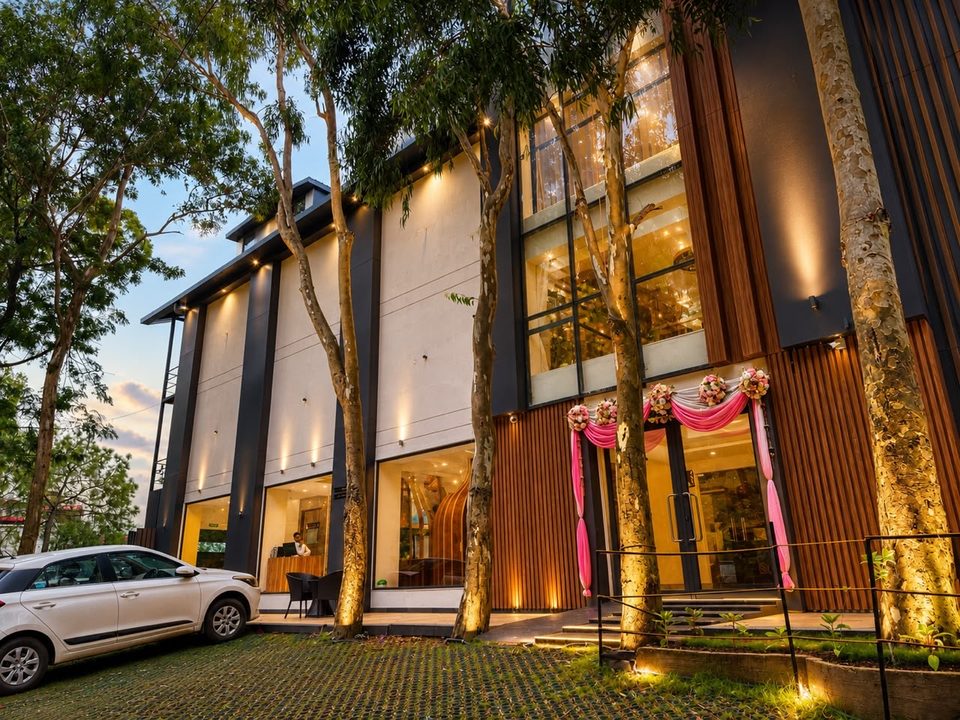 Hotel entrance and wood-slat facade lit up at dusk at Solace Suites