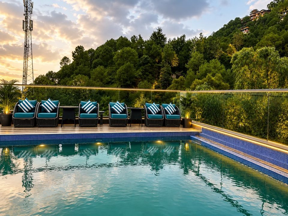 Rooftop pool with lounge chairs and pine-covered hills at sunset at Solace Suites